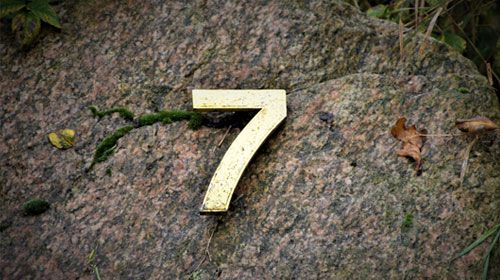 The number 7 on a stone representing 7 facts about Online Exams