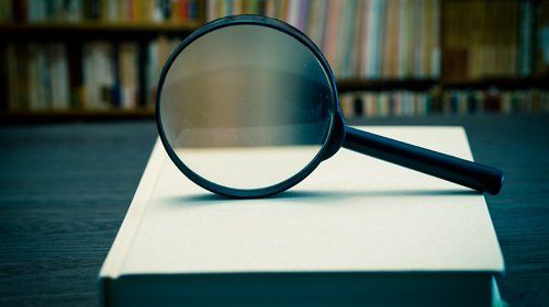 Magnifying glass on books representing examining experts in assessment